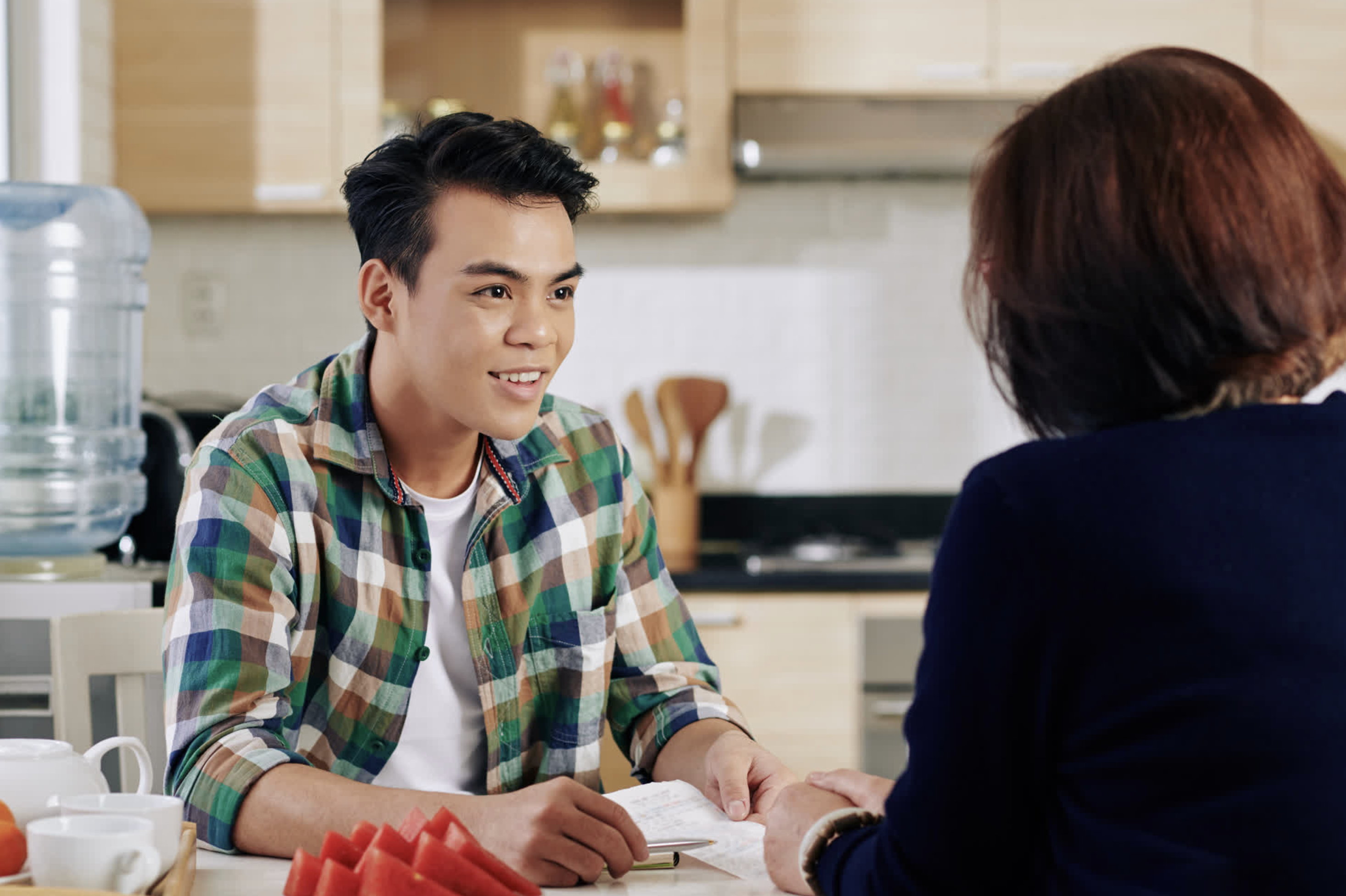 Young man at a kitchen table learning about buying a home with student loans